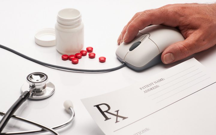 Prescription medicine and pharmacist hand on  computer mouse